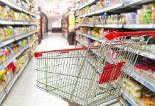 Empty shopping cart in grocery store aisle.