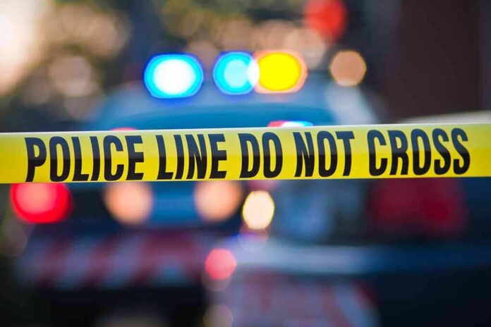 56280433 featured image Yellow police tape with police lights blurred behind