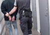Officer escorting handcuffed person down hallway