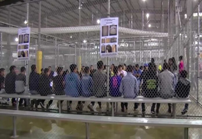 People sitting on benches inside a fenced facility