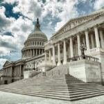 Capitol building with columns and cloudy sky