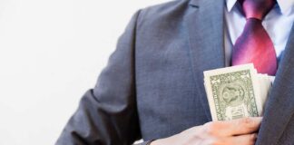 Person in suit putting dollars in jacket pocket