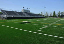 Empty football field with bleachers in background