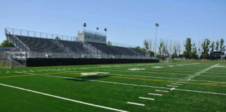 Empty football field with bleachers in background