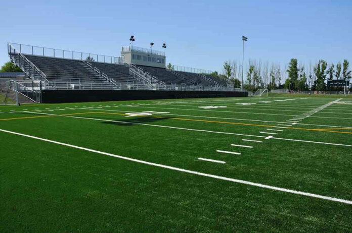 55132081 Empty football field with bleachers in background