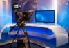 Television studio setup with a camera and monitor on a modern desk