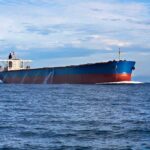 A large cargo ship sailing on the ocean under a blue sky