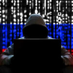 Hacker in hoodie with Russian flag background and code.