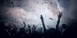 Crowd celebrating under confetti and bright lights.