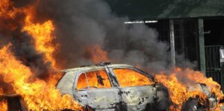 A car engulfed in flames with thick smoke billowing into the air
