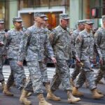 Group of soldiers marching in a military parade on a city street