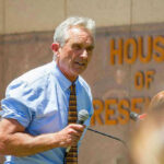 Man speaking into microphone outside House of Representatives.