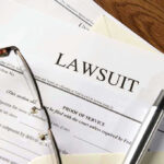 Lawsuit papers with glasses and pen on table.