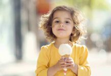 Elections Chief Accused—Ice Cream Scandal Explodes A young child with curly hair holding an ice cream cone outdoors