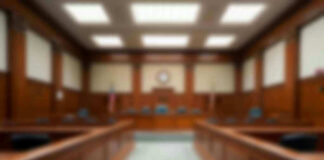 Empty courthouse courtroom with wooden benches and chairs.