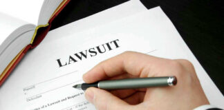 Hand holding pen, filling out lawsuit form.