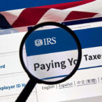 Political Titans Targeted—NEW IRS Boss Fires Back Magnifying glass over IRS website for paying taxes.