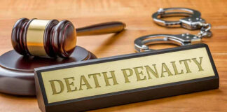 Gavel, handcuffs, and Death Penalty sign on desk.