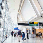 Trump Blocks Airline Payouts – Travelers Left Hanging People walking in a brightly lit airport terminal.