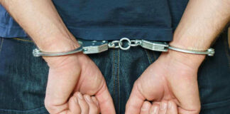 Person in handcuffs behind their back.