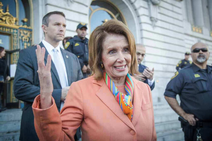 Woman in orange blazer speaking, surrounded by security personnel.