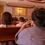 People sitting in church pews during service.