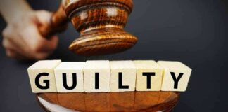 A gavel striking down next to wooden blocks spelling 'GUILTY'