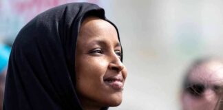 Woman wearing a black hijab looking thoughtfully into the distance