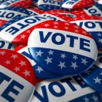A pile of colorful buttons with the word VOTE and stars, symbolizing election participation