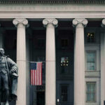 US Treasury Department building with statue and flag.