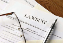 Lawsuit papers with glasses and pen on table.