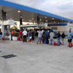 People waiting in line at a gas station with fuel containers