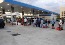 People waiting in line at a gas station with fuel containers