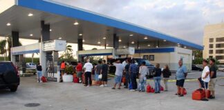 People waiting in line at a gas station with fuel containers