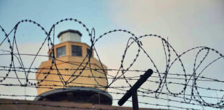 Barbed wire in front of a prison tower.