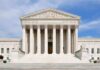 Front view of the Supreme Court building with large columns and steps under a blue sky