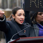 Person speaking passionately at outdoor event.