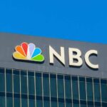 NBC logo displayed on a corporate building against a blue sky