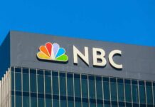 Newsman HERO Saves Teen From Fiery Death NBC logo displayed on a corporate building against a blue sky