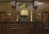 Interior of a courtroom featuring a judges bench and American flag