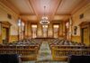 Married Judge Has Sex With Officer In Courthouse! Interior view of a historic courtroom with wooden furnishings and chandeliers