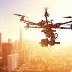 Papa Johns’ Bold Drone Delivery Gamble A drone flying over a city skyline during sunset