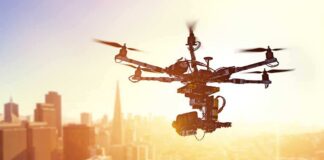 A drone flying over a city skyline during sunset