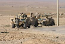 Two military humvees with soldiers in a desert landscape