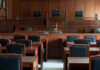 Ninth Circuit Judge CHARGED In Shocking Assault Case! Empty courtroom with wooden furnishings and judges bench.