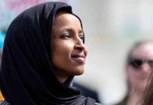 Ilhan Omar Now BROKE – Numbers Whiplash Stuns Congress! Woman wearing a black hijab looking thoughtfully into the distance