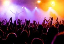 Father FALLS To Death During Concert – Audience STUNNED! Crowd at a concert with raised hands and colorful stage lights