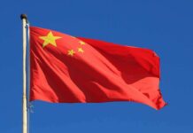 China Takes U.S Citizen HOSTAGE – Sparks International Fury! Chinese national flag waving against a clear blue sky
