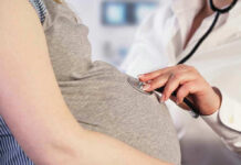 Doctor uses stethoscope on pregnant womans belly.