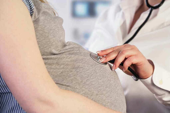261991445 Doctor uses stethoscope on pregnant womans belly.